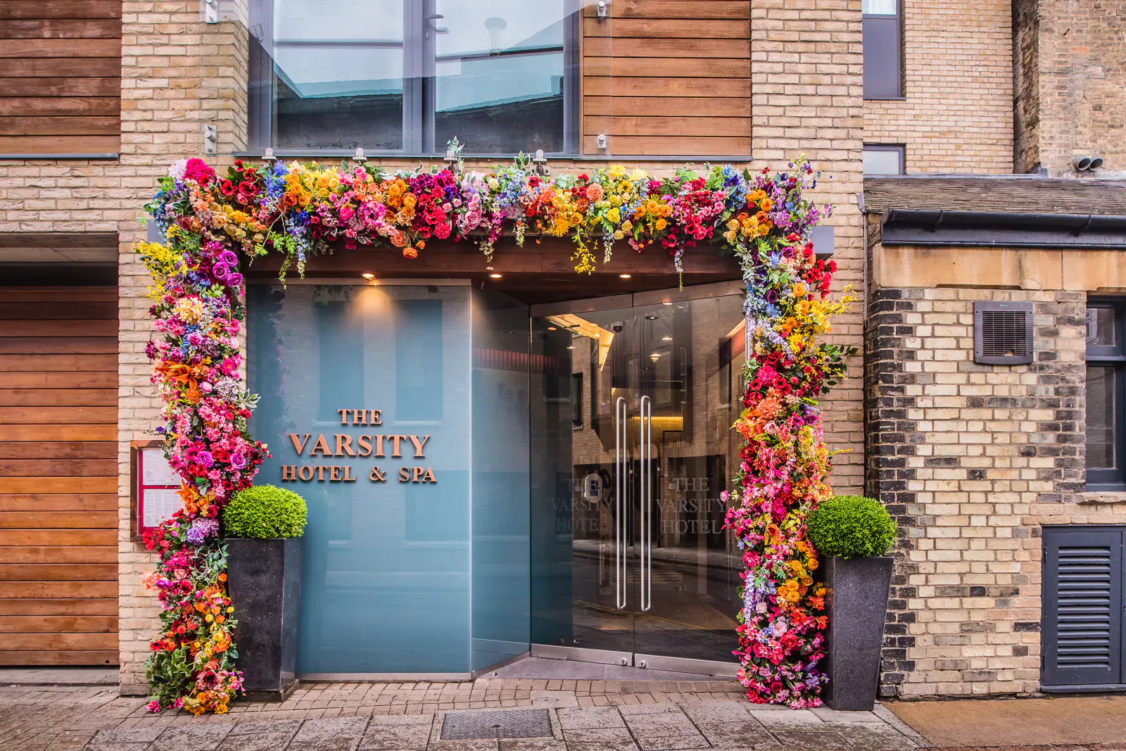 The Varsity Hotel & Co entrance framed by vibrant multicolored floral arches on brick building