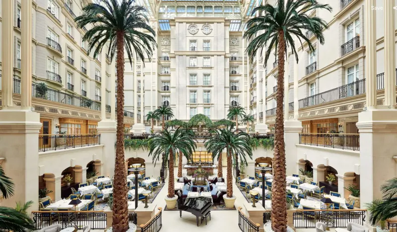 Grand Winter Garden atrium at The Landmark with tall palm trees, grand piano, tables, and multi-level balconies.