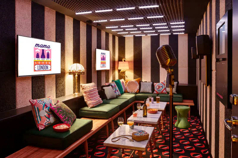 Mama Shelter East London gallery: striped lounge with green sofa, pillows, drinks table, mic stand, neon 'Mama' signs.