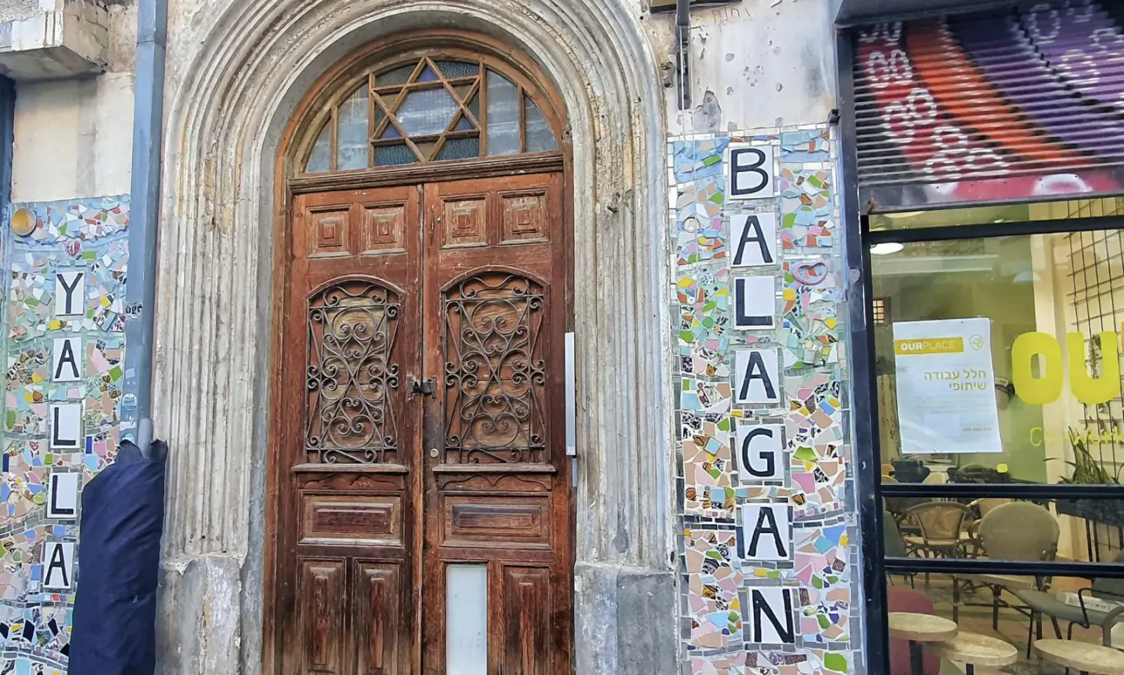 Ornate wooden doors of historic synagogue on Nachalat Binyamin Street, Tel Aviv, with 'BALAGAN' tiled wall art and Star of David.