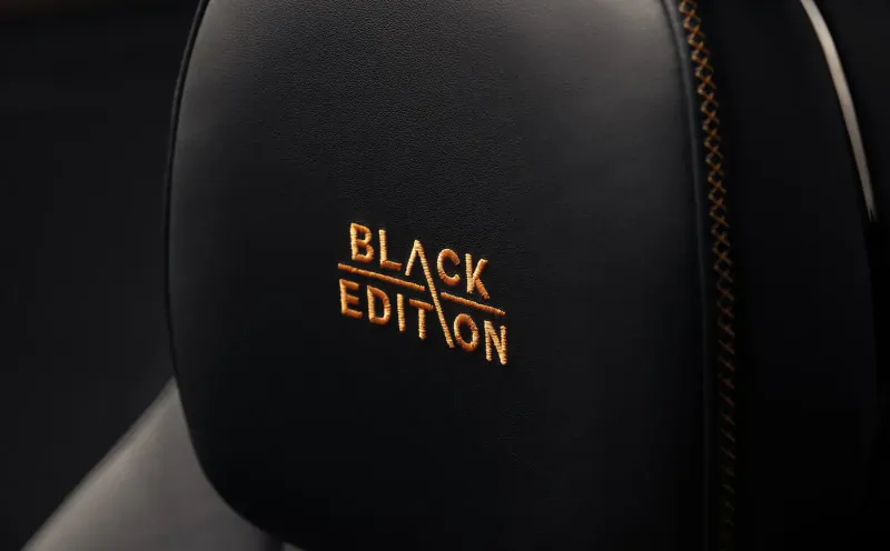 Black leather car headrest with gold 'BLACK EDITION' embroidery