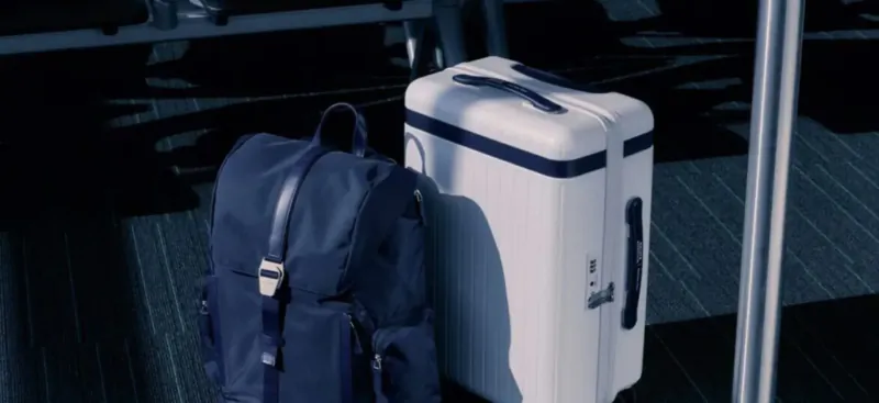 Navy backpack and white hard-shell suitcase on airport terminal floor