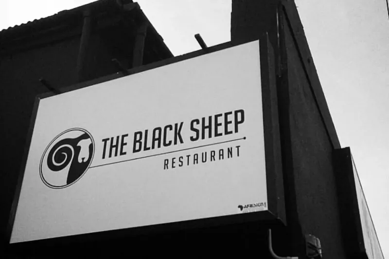 Black and white photo of The Black Sheep Restaurant sign on a building facade on Kloof Street.