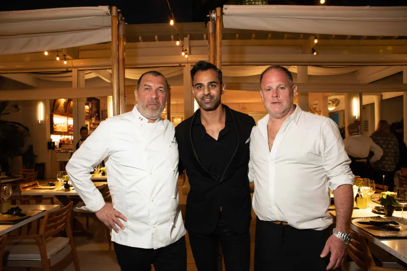 Pat Martin in chef whites stands with two men in suits at outdoor South Beach Food festival patio