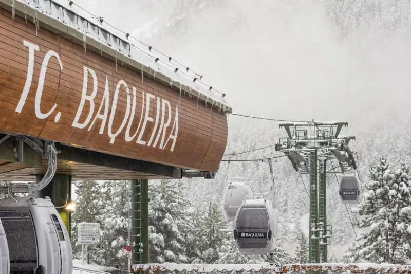 TC Baqueira cable car station with gondolas ascending snowy Pyrenees slopes in Val d'Aran.