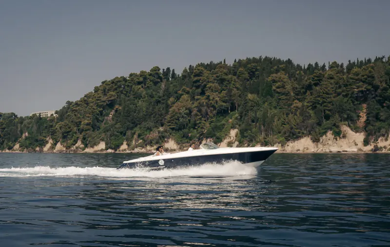 White speedboat racing across water near tree-covered hills at Angsana Corfu Resort and Spa
