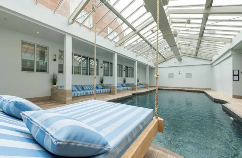 Elegant indoor pool at Manor House Hotel and Spa with glass ceiling, striped lounge beds, and daybeds.