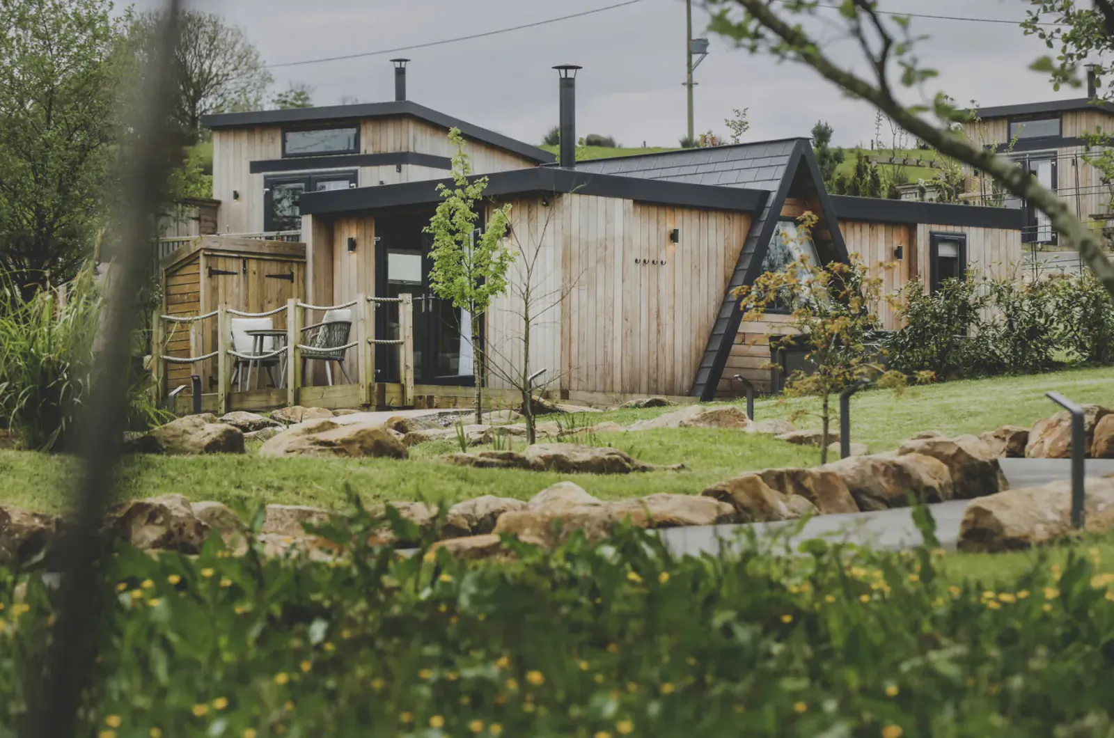 Modern wooden cabins at Everything Retreat in Ribble Valley, surrounded by lush green gardens and trees.