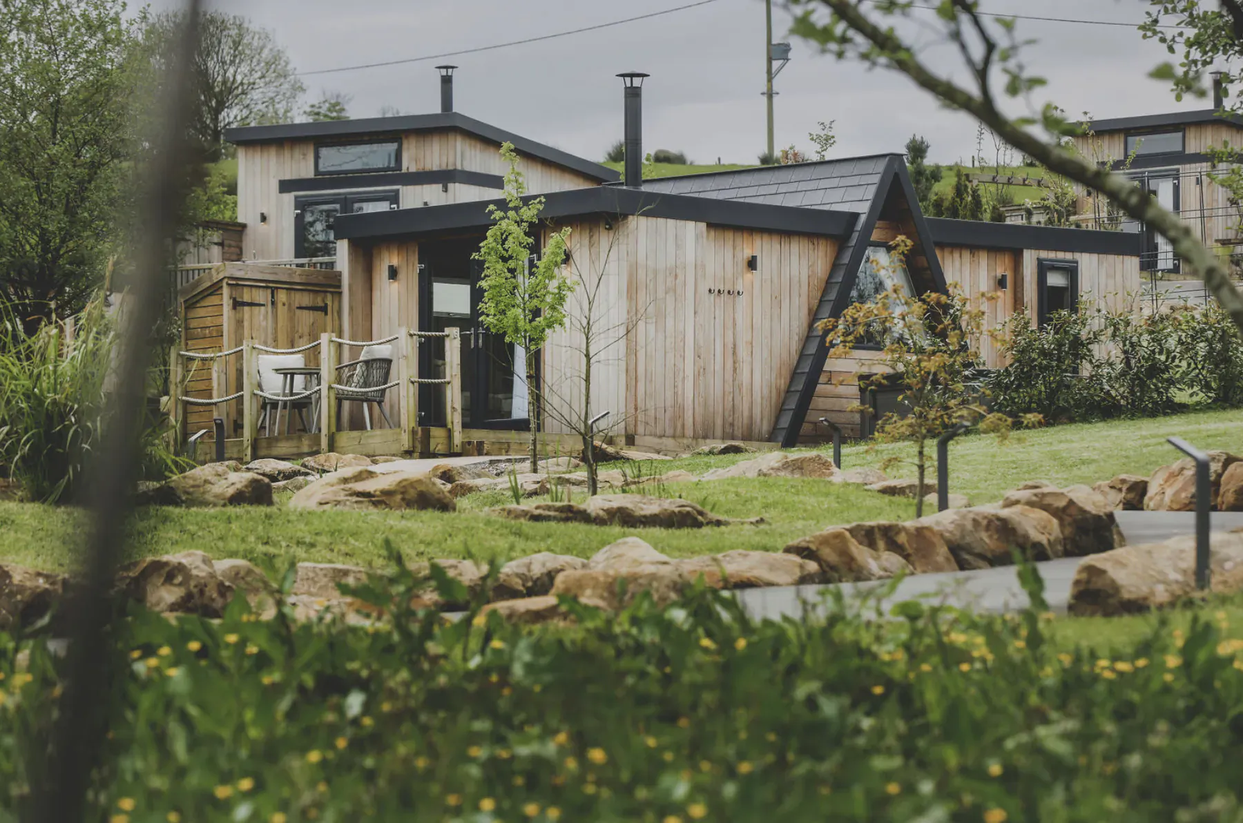 Modern wooden cabins at Everything Retreat in Ribble Valley, surrounded by lush green gardens and trees.