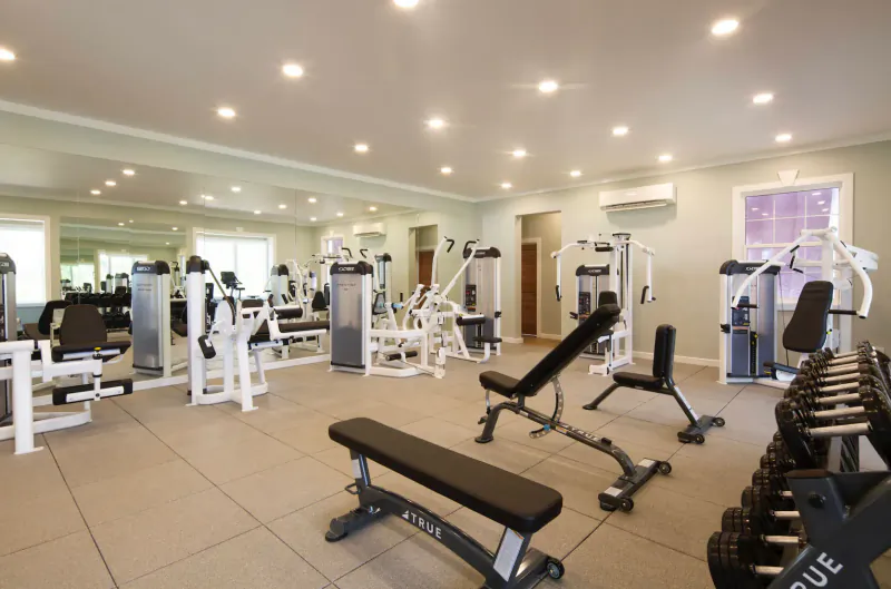 Spacious gym at Hammock Cove resort with weight machines, benches, dumbbells, and mirrors