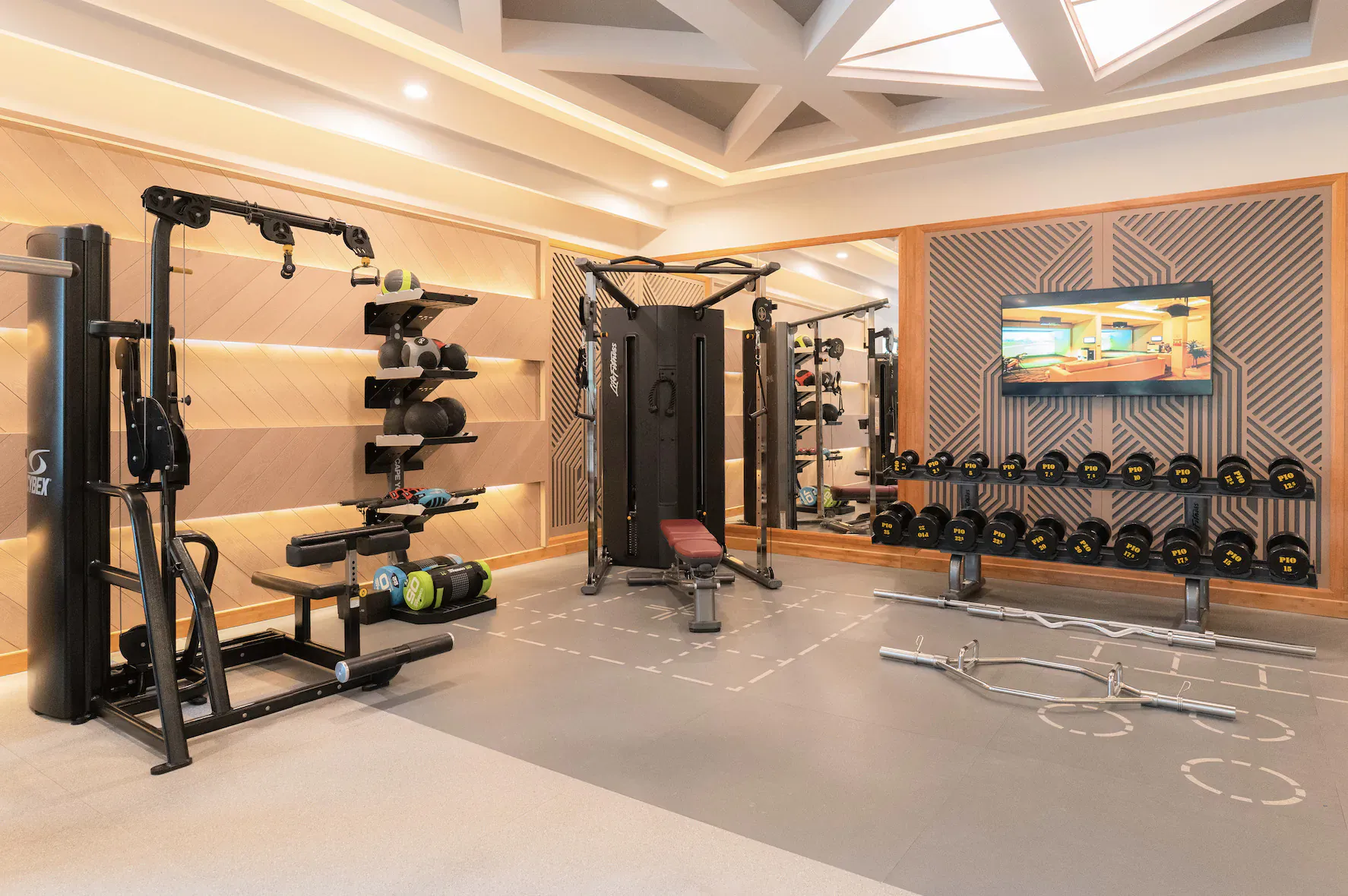 Modern gym at Hideaway Beach Resort with cardio machines, weights, dumbbells, and rubberized floor