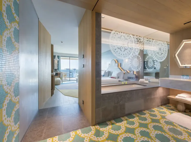 Luxurious W Algarve hotel suite with ocean-view bedroom, freestanding tub, and mosaic-tiled bathroom