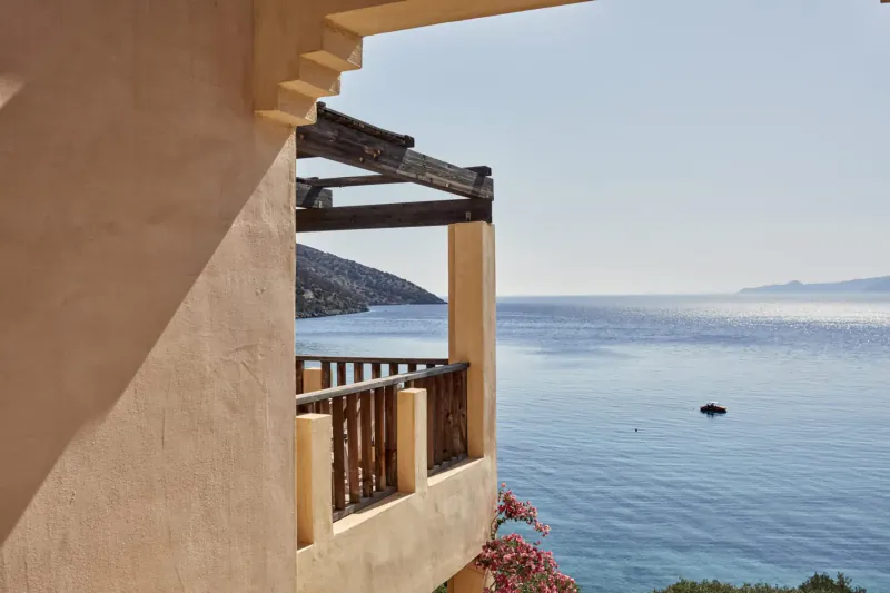 Balcony of Candia Park Crete hotel overlooking the calm blue sea, with distant mountains and bougainvillea.