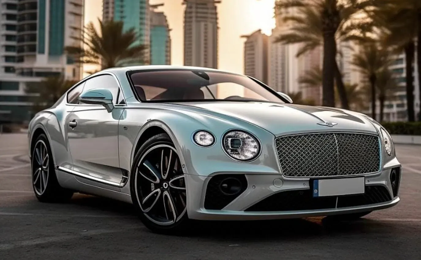 Silver Bentley Continental GT parked in UAE cityscape at sunset with skyscrapers and palms