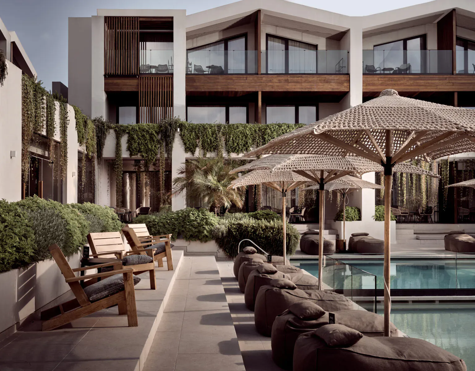 Contessina Hotel Zakynthos: modern luxury resort with tiered white buildings, ivy walls, palm trees, sun umbrellas, lounge chairs, and pool.