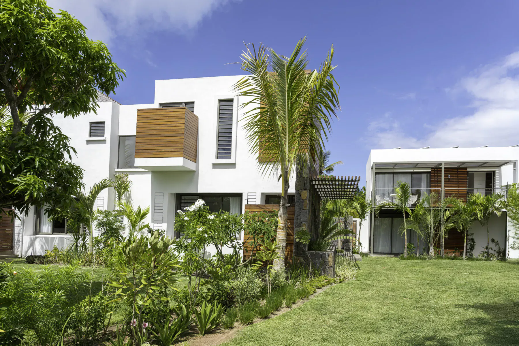 Modern white Villa Diamond with wooden accents and palm trees in lush tropical garden, Belle Mare, Mauritius