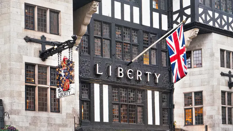 Liberty London store facade with Tudor architecture, Union Jack flags, and ornate hanging sign.