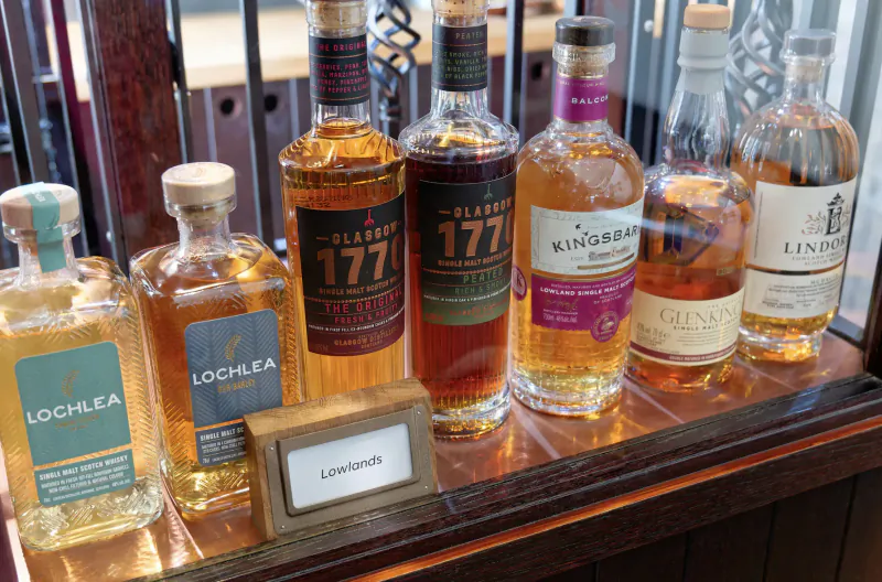 Wooden display case of whisky bottles: Lochlea, Lochnlea, Old Perth 177, King’s Inch, London, with Lochnlea label.