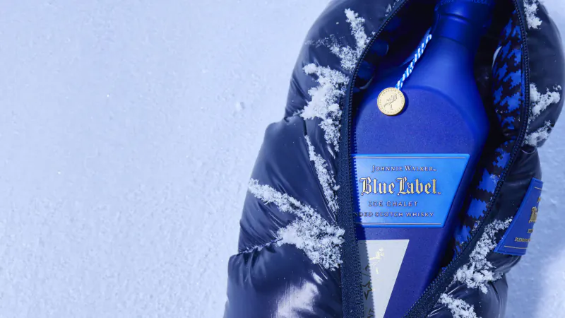 Johnnie Walker Blue Label bottle nestled in a snowy puffer jacket, après ski style.