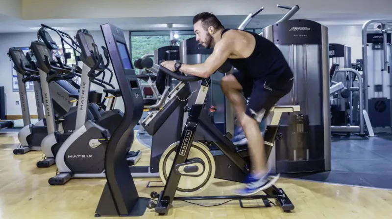 Man with beard cycling intensely on stationary bike in luxury gym with modern equipment