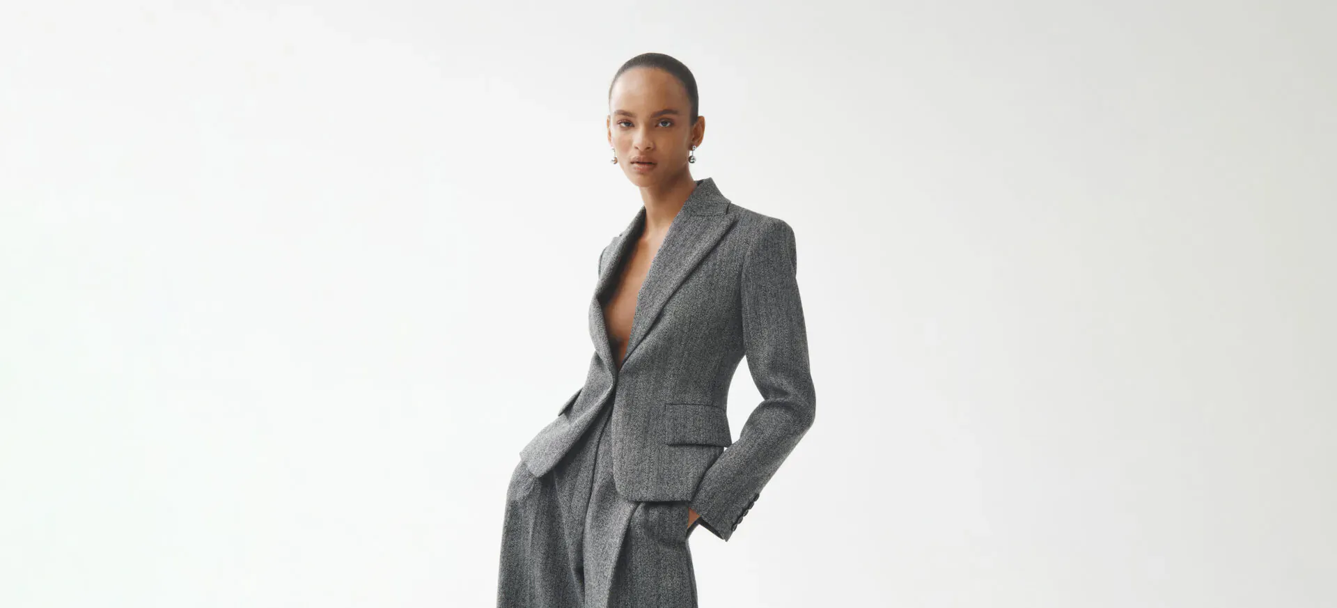 Scanlan Theodore model in open grey blazer and trousers, hand in pocket, quiet luxury style