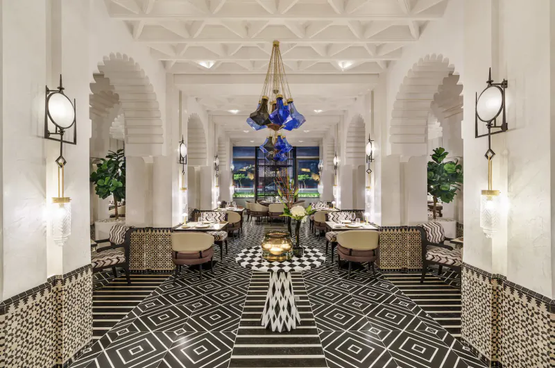 Elegant hotel lobby at Fairmont La Marina Rabat-Salé with white arches, blue chandelier, black-white tile floor, and lounge seating