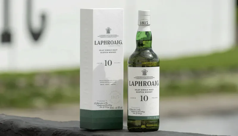 Laphroaig 10 Year Old Scotch whisky bottle and white box on stone surface outdoors