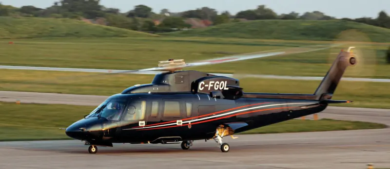 Black Bell 412 helicopter C-FOL taxiing on runway at Le Mans, grassy fields and hills in background.