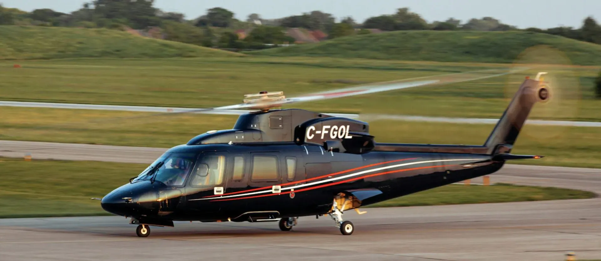 Black Bell 412 helicopter C-FOL taxiing on runway at Le Mans, grassy fields and hills in background.