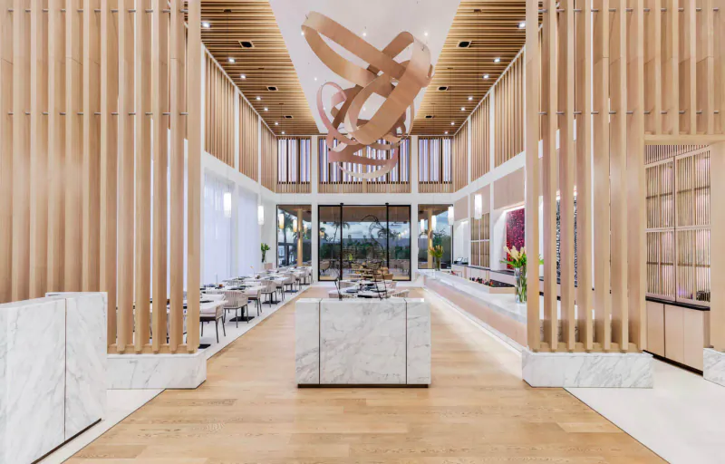 Spacious Silversands Grenada gallery with wooden slat walls, looping ceiling sculpture, marble counter, dining area, and garden view.