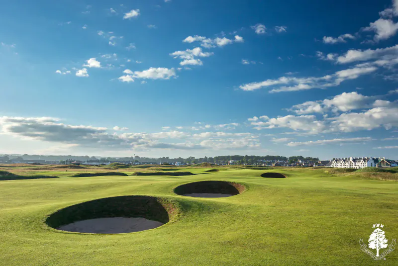 Carnoustie golf course bunkers on lush green fairway under blue sky with scattered clouds