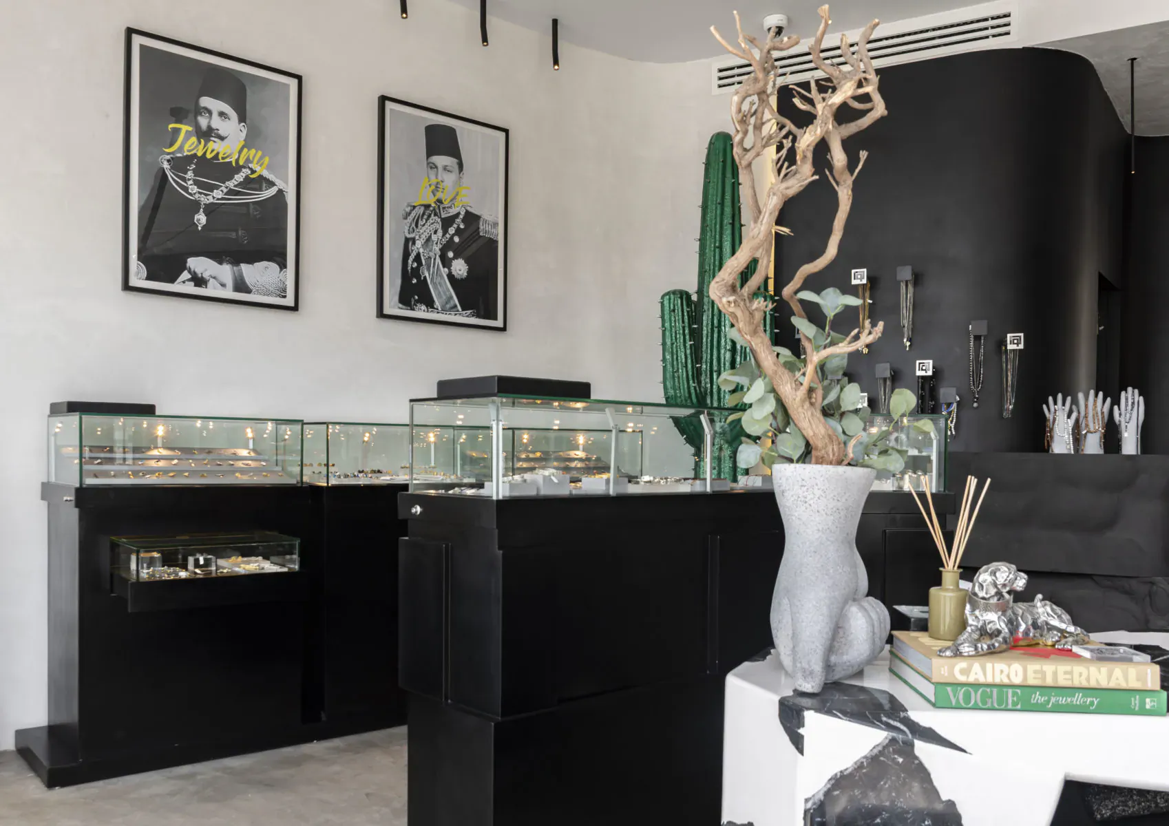 Huwa men's jewellery flagship store in Cairo: display cases with watches and rings, black decor, cactus, 'Dandash' portraits.