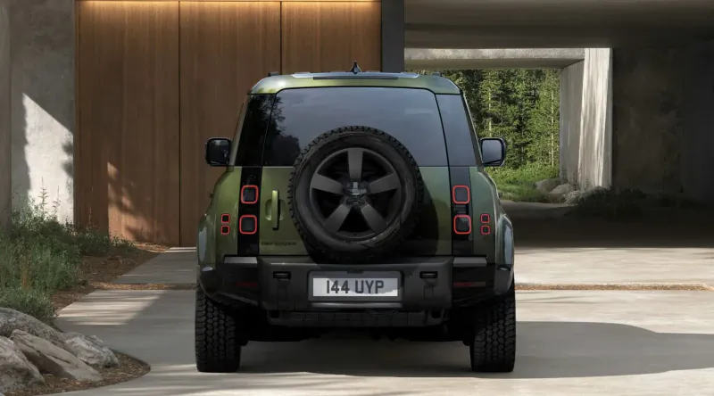 Rear view of green Land Rover Defender 4x4 with license plate '14 DYF' parked under modern wooden archway.