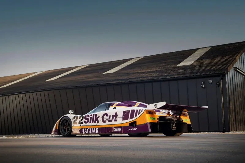 Silk Cut Jaguar XJR-9 race car with #22 livery parked in front of a black hangar at London Concours 2024