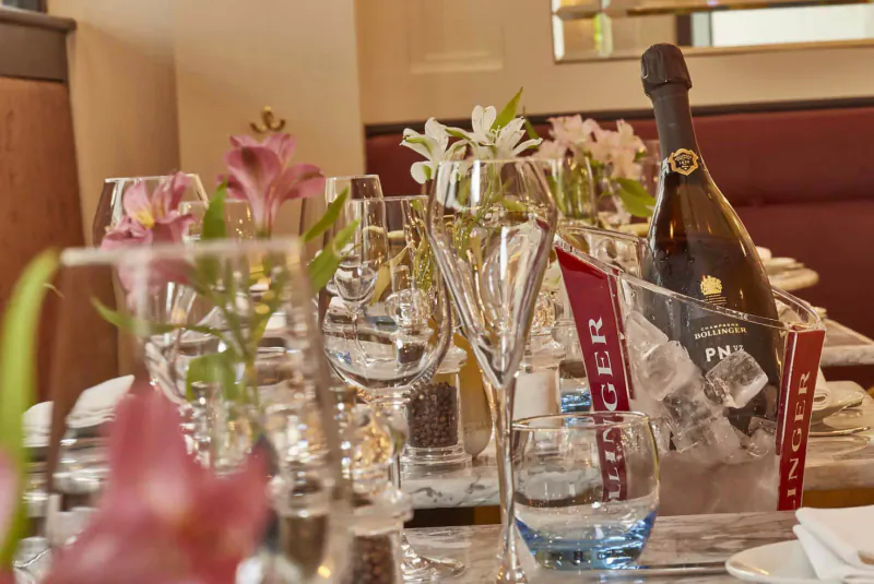 Elegant restaurant table with pink flowers, Veuve Clicquot champagne bottle in ice, and wine glasses at 28-50 Oxford Circus