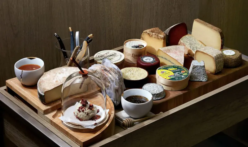 Assortment of artisanal cheeses, charcuterie, dips, honey, and bread on wooden board at Saint Pierre restaurant.