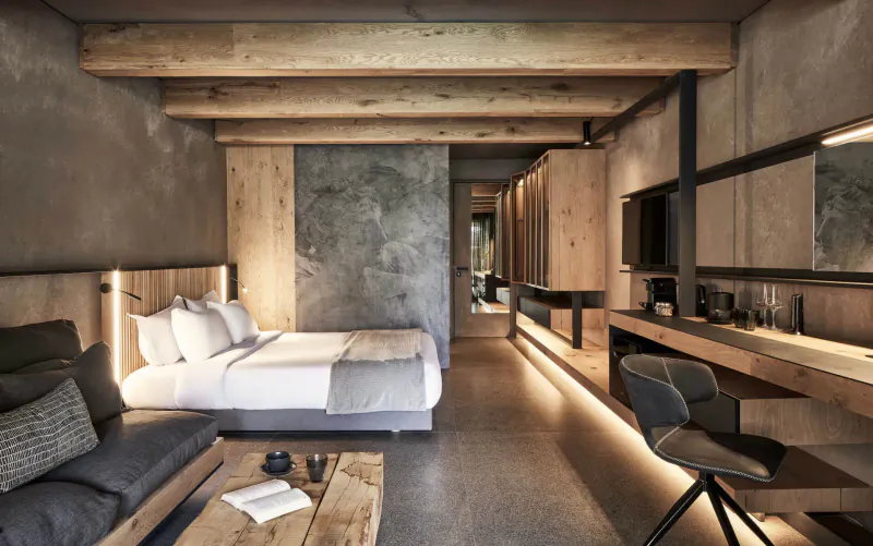 Modern wooden-beamed hotel room at Elysium Boutique Hotel Crete with king bed, desk, and ambient lighting.