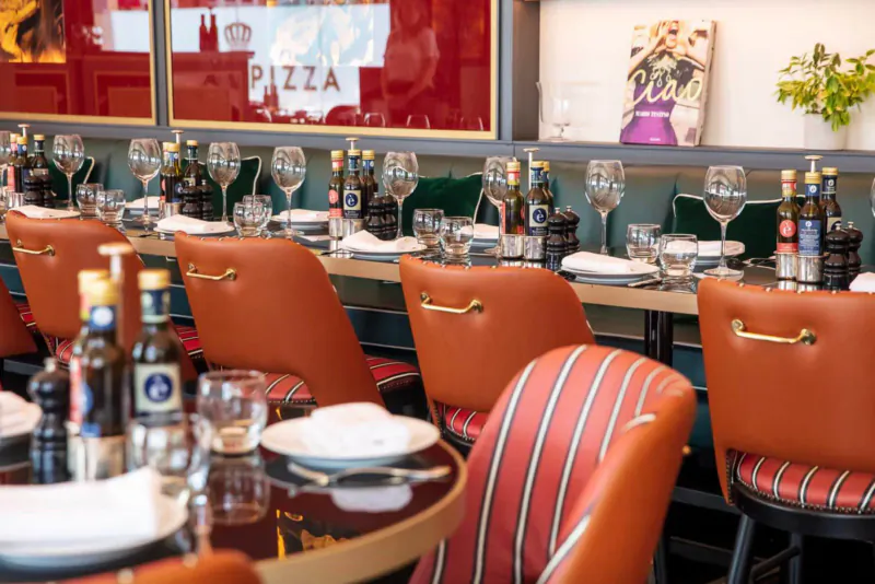 Crazy Pizza Marylebone interior: elegant tables with wine bottles and glasses, red 'PIZZA' sign, and artwork.