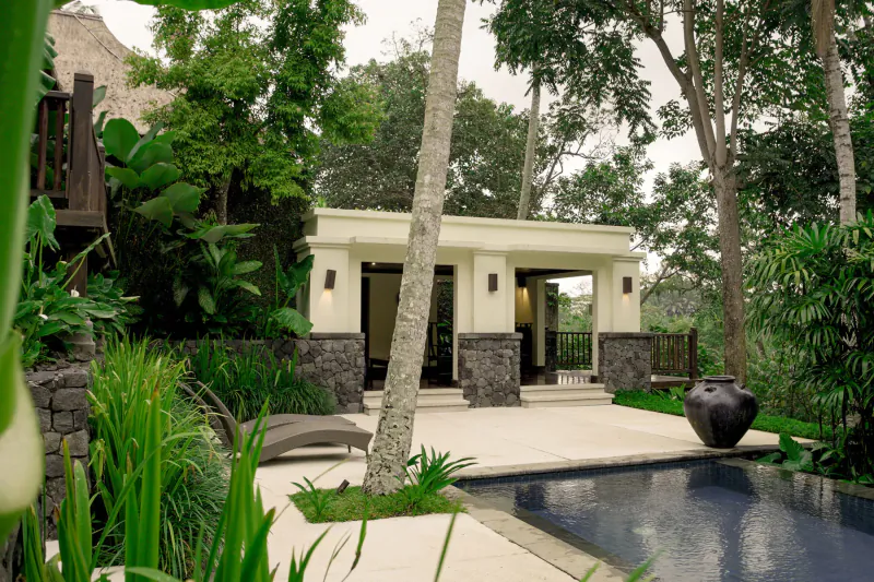 Tropical villa with open pavilion, infinity pool, lounge chair, and lush forest surroundings in Ubud Bali