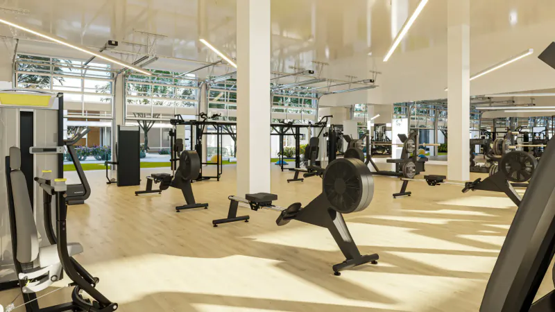Spacious modern gym at Ariva Serviced Residences with rowers, weight machines, and large windows