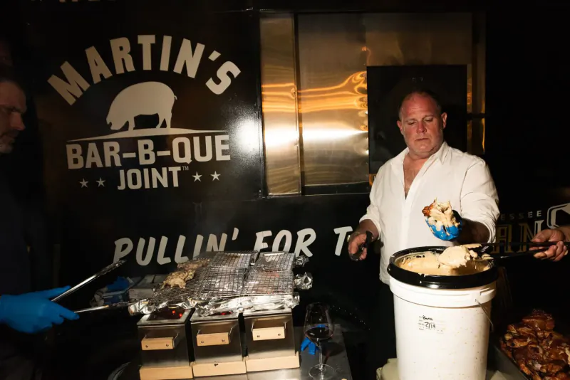 Pat Martin at Martin's BBQ Joint booth scoops pulled pork from bucket at South Beach Food festival