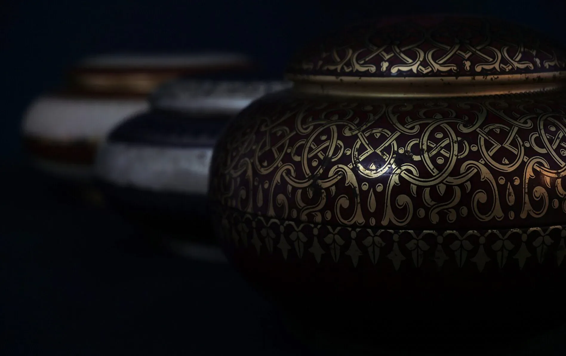 Close-up of ornate marble urns with gold filigree patterns on dark background