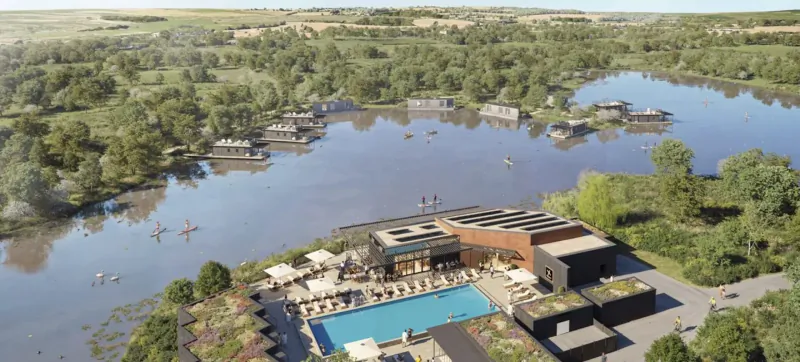 Aerial view of Luxuria Lifestyle Escapes resort at Silverlake Dorset: modern buildings, infinity pool, surrounded by lush wetlands and lake.