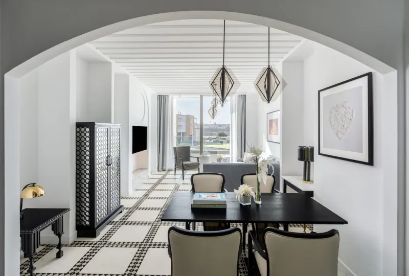 Elegant Fairmont hotel suite with black-and-white checkered floor, dining table, chairs, city view through arched windows.