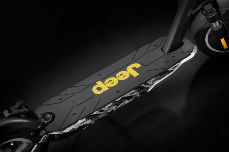 Close-up of Jeep electric scooter's black deck with yellow 'Jeep' logo and rugged texture.