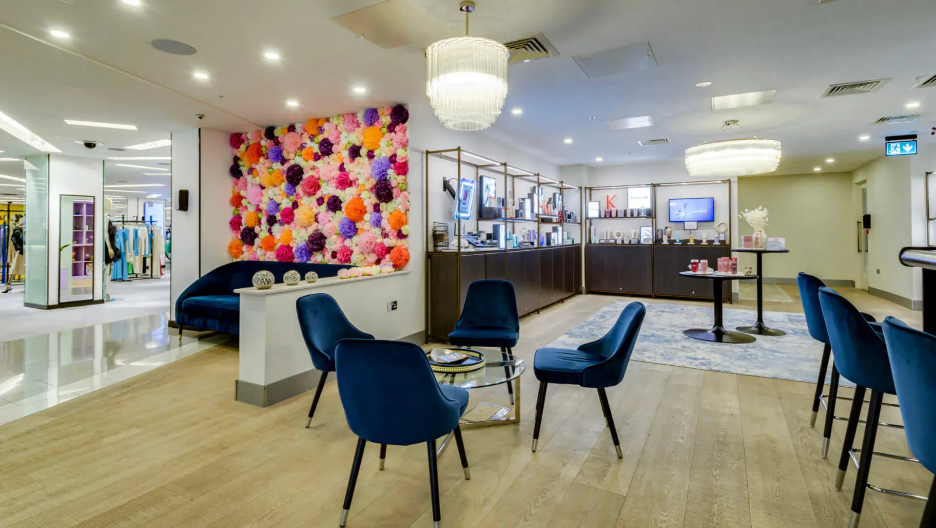 Jo Hansford hairdressing salon reception with vibrant floral wall, blue velvet chairs, reception desk, and mall setting.