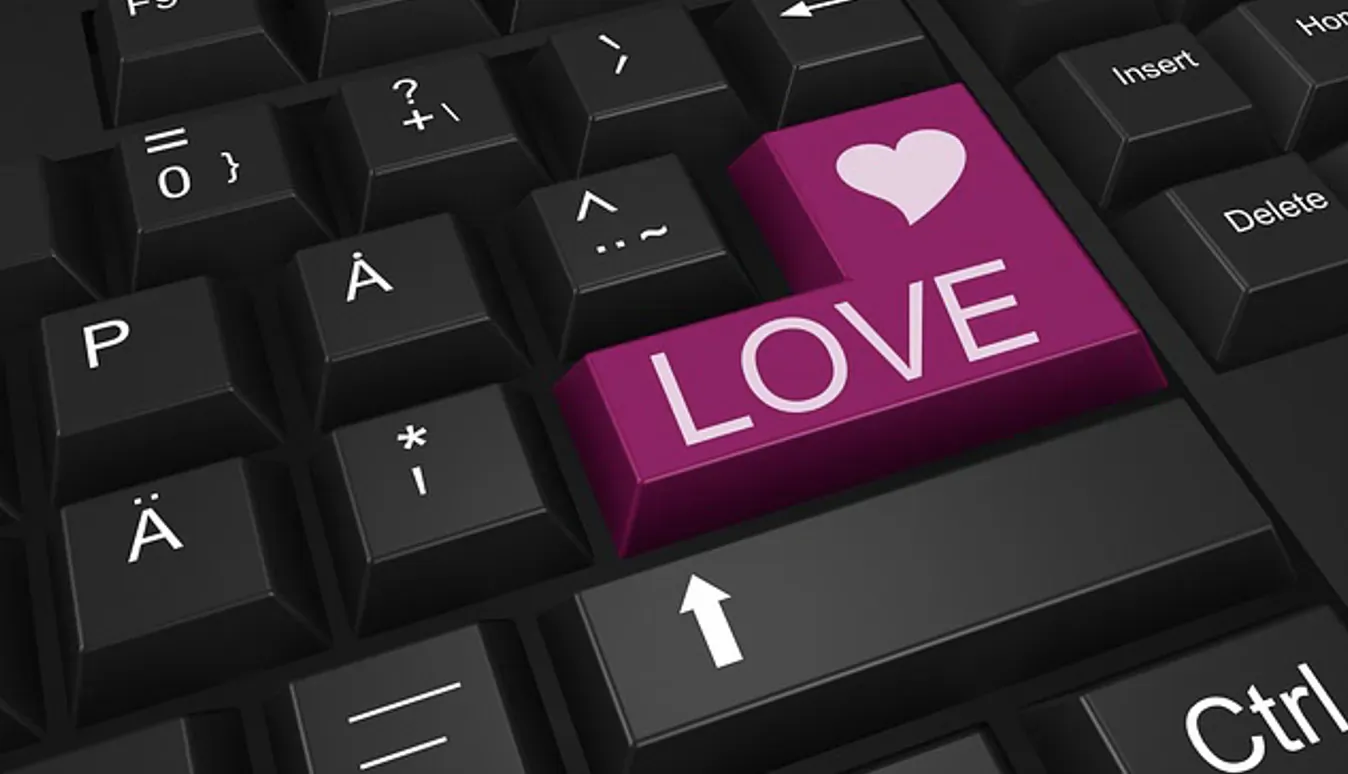 Pink keyboard key labeled 'LOVE' with heart icon, on black keyboard, evoking online dating.