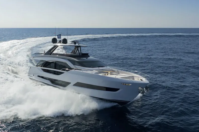White luxury Ferretti yacht speeding across the sea, creating a large wake, at Genoa Boat Show.