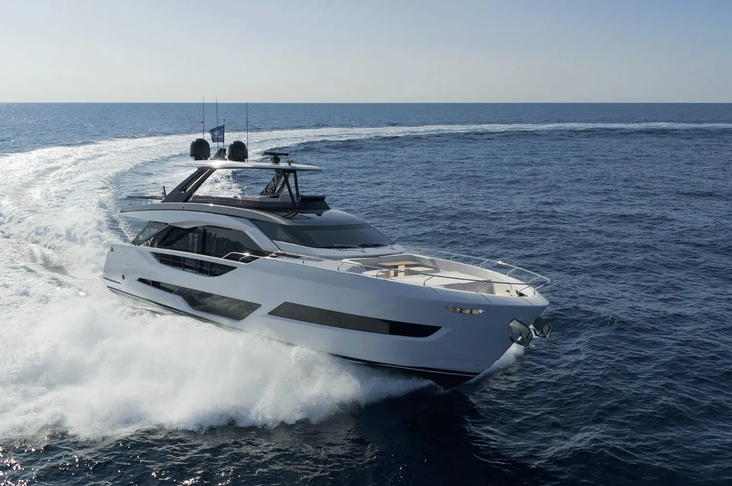 White luxury Ferretti yacht speeding across the sea, creating a large wake, at Genoa Boat Show.