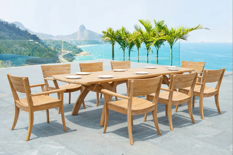 Teak rectangular dining table with armchairs on terrace overlooking ocean, palm trees, and mountains